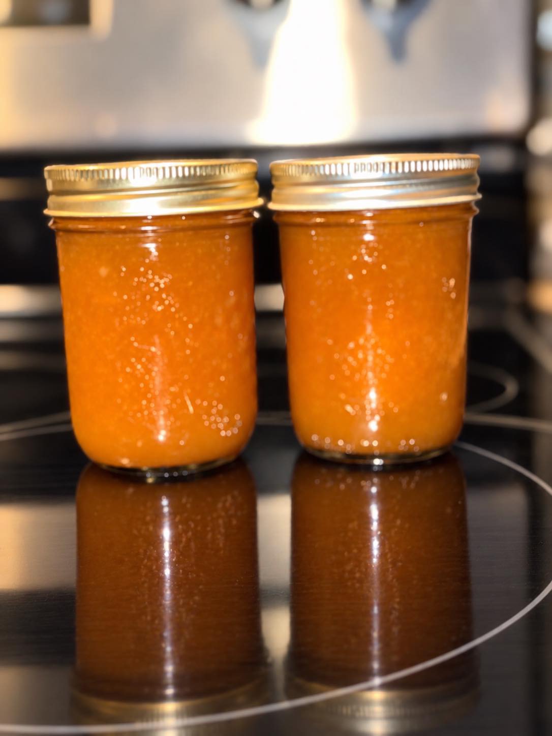 Two jars of golden preserves on the stovetop