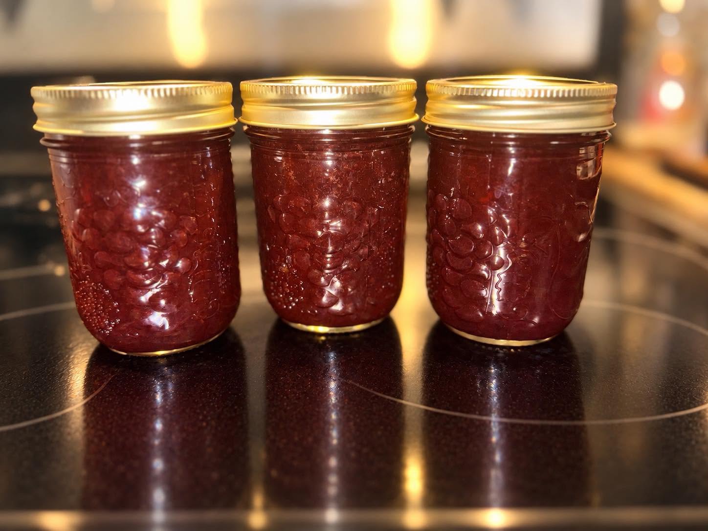 Three jars of deep red jam with gold lids
