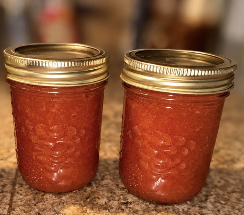 Two jars of red preserves with gold lids